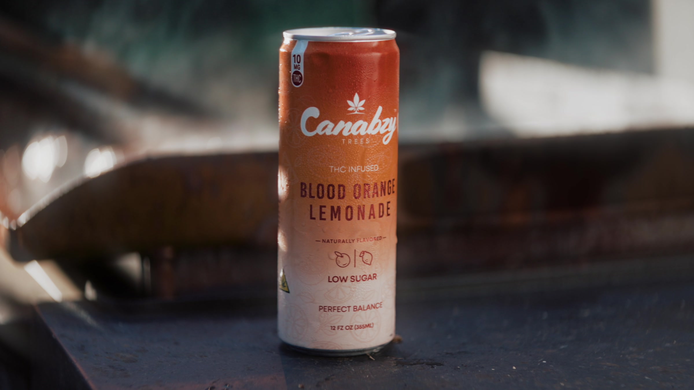 A chilled Canabzy Blood Orange Lemonade can standing on the grill rail, condensation on the label